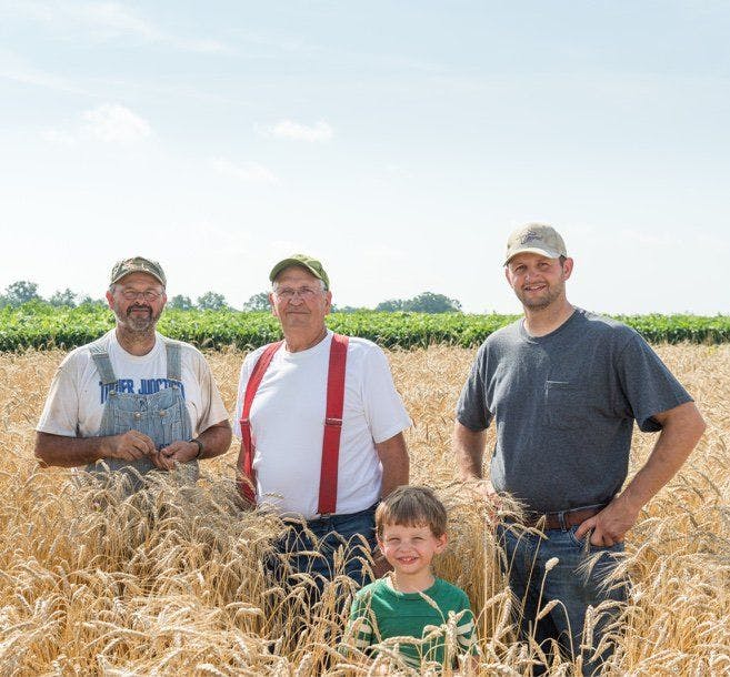 A family of farmers standing in their field.