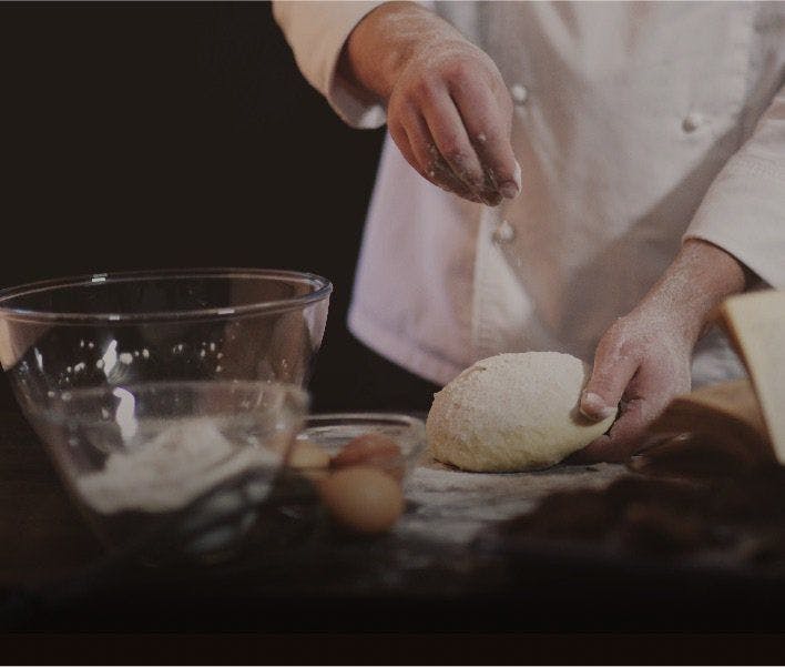 A chef sprinkling flour over some homemade dough.